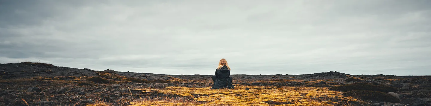Woman sitting near volcanic scenery