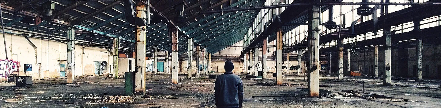 A rear view of a man standing in an abandoned factory