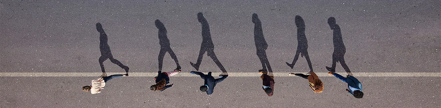 Top down view of people waking in the middle of a street casting shadows