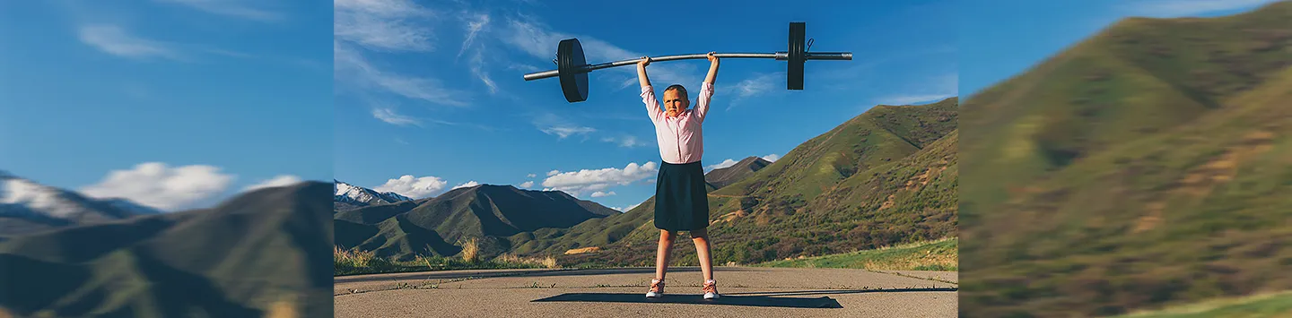 A young girl dressed as a businesswoman is lifting weights
