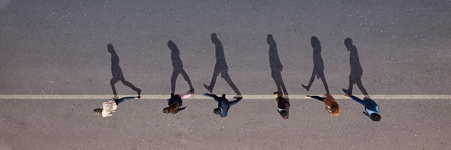 Top down view of people waking in the middle of a street casting shadows