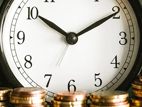 Clock surrounded by piles of coins