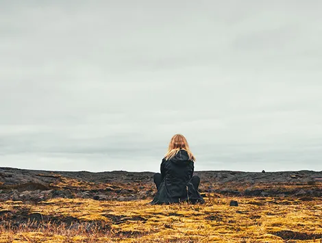 Woman sitting near volcanic scenery