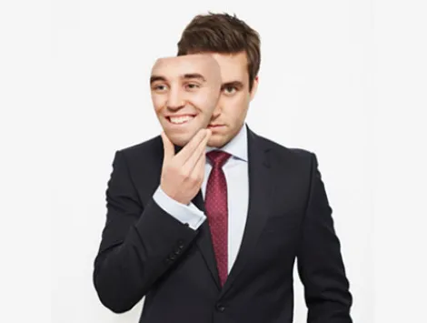 Businessman holding mask over his face 