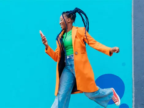 Italy, Milan, Woman with braids jumping against blue wall